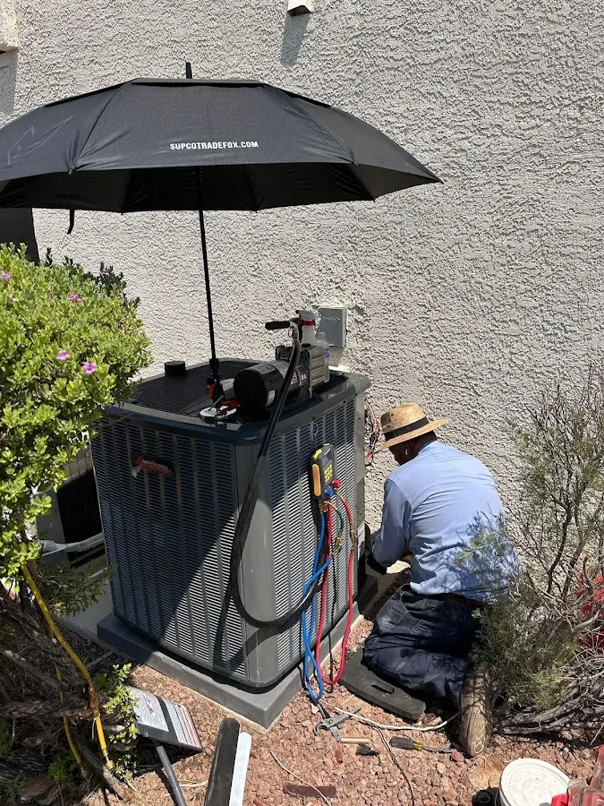 HVAC technician performing outdoor AC maintenance in Adel