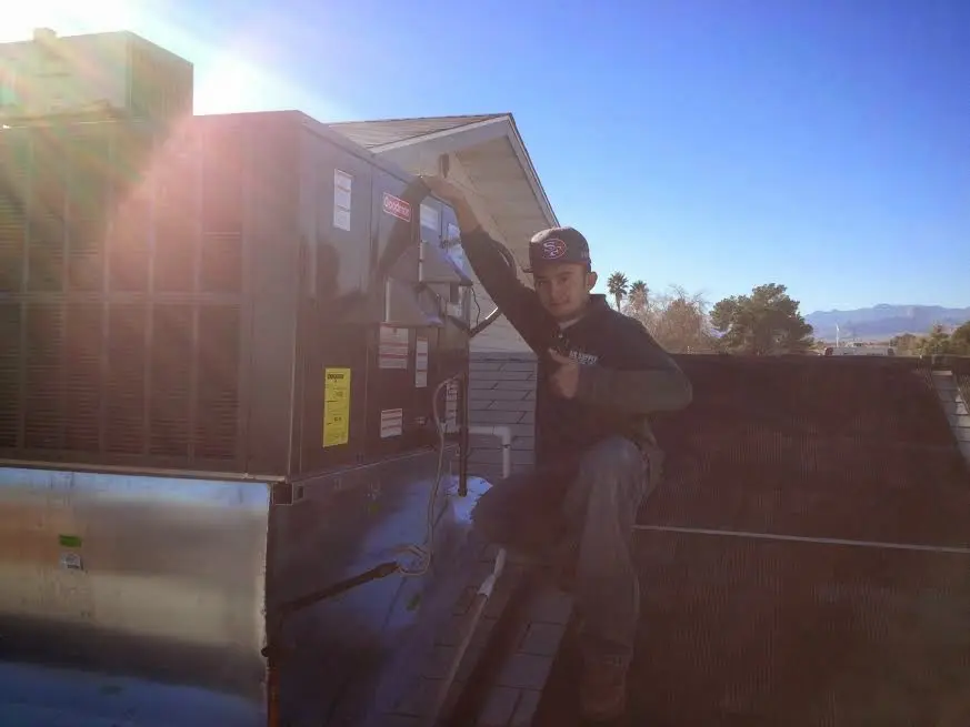HVAC technician performing AC Tune-Up on a rooftop unit in Adel